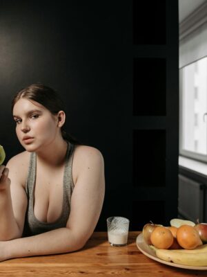 Woman enjoying an apple and glass of milk, promoting a healthy lifestyle indoors.